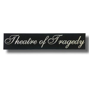 Può includere: Un cartello rettangolare nero con la scritta "Theatre of Tragedy" in lettere bianche e corsive. Il cartello ha una leggera ombra, che suggerisce che sia in rilievo.