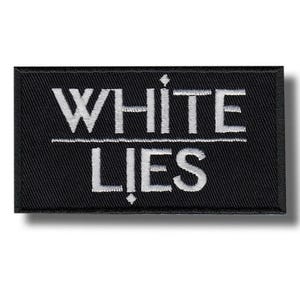 Może przedstawiać: Czarna prostokątna naszywka z białymi słowami "WHITE" nad "LIES" w kroju bezszeryfowym. Biała pozioma linia oddziela te dwa słowa. Naszywka ma czarną obwódkę i cień.