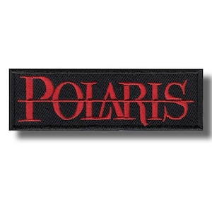 May include: Black rectangular embroidered patch with the word "POLARIS" in red, stylized lettering. The word is bisected by a horizontal red line. The patch has a black border.