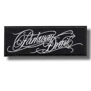 Puede incluir: Parche rectangular negro con texto bordado blanco "Parkway Drive" en una fuente de escritura estilizada. El parche tiene un borde negro y un efecto de sombra.
