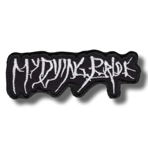Puede incluir: Parche bordado negro con el texto blanco "MY DYING BRIDE". El parche tiene una forma irregular distintiva con un borde negro. La letra está en una fuente estilizada, creando un impacto visual llamativo.