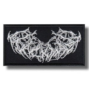 Peut inclure: Écusson rectangulaire noir avec un motif blanc symétrique et complexe. Le motif semble brodé et a une forme organique complexe. L'écusson est probablement destiné aux vêtements ou aux accessoires.