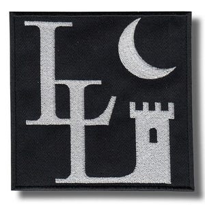 Puede incluir: Parche cuadrado negro con diseño bordado en blanco. El diseño presenta las letras "LE" en una fuente estilizada, una luna creciente y una torre de castillo. El parche tiene un borde negro y una sombra.