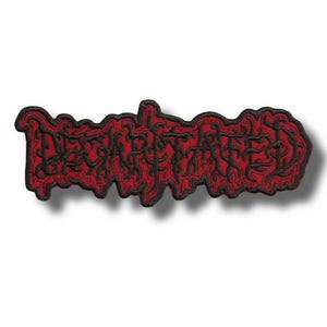 May include: A red and black embroidered patch featuring the word "DECAPITATED" in a stylized, gothic font. The patch has a black border and a shadow effect, giving it a three-dimensional appearance. The design is bold and eye-catching.