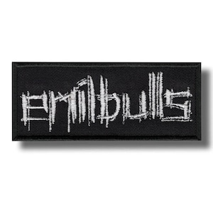 Puede incluir: Un parche rectangular negro con el texto blanco "Erimbulls" en una fuente estilizada y desgastada. El parche tiene una textura tejida y un sutil efecto de sombra, sugiriendo un diseño en relieve.
