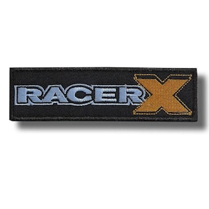 Puede incluir: Parche rectangular negro con el texto "RACER" en azul claro y "X" en dorado. El parche está bordado con un borde negro y probablemente está diseñado para coserse en ropa o accesorios.