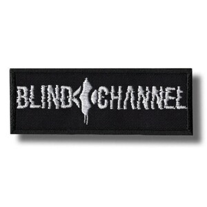 May include: A black rectangular patch featuring the white embroidered text "BLIND CHANNEL". A white graphic is positioned between the words. This patch is designed for application on clothing or accessories.