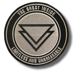Op de afbeelding: Ronde geborduurde patch met de tekst "THE GHOST INSIDE" bovenaan en "LIMITLESS AND UNBREAKABLE" onderaan. De patch heeft een zwarte rand, een lichtgrijze kern en een zwart dubbel driehoekontwerp.