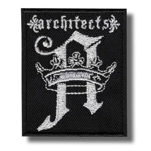 Op de afbeelding: Zwart rechthoekig embleem met wit geborduurd tekst en ontwerp. Het woord "architects" is bovenaan gebogen. Een gestileerde letter "A" is gecentreerd, bekroond.