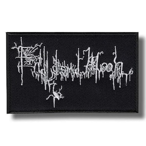 May include: Black rectangular patch with white embroidered text. The text appears to be a band name or logo in a stylized, gothic font. The patch has a woven texture and a dark shadow.