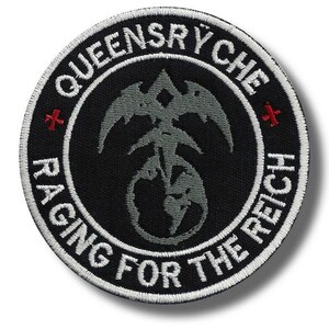 May include: A circular black patch with white embroidered text and a gray emblem. The text reads "QUEENSRYCHE" and "RAGING FOR THE REICH". The emblem is a stylized design with a bird-like shape. Two red crosses are also present.