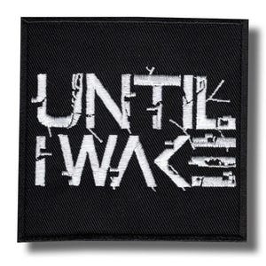 May include: Square black patch with white embroidered text reading "UNTIL I WAKE". The text has a distressed, textured appearance. The patch has a black border and is likely designed to be sewn onto clothing or accessories.