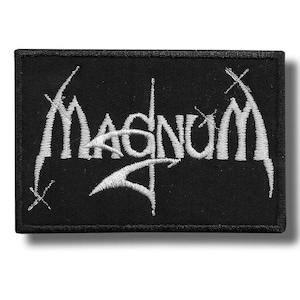 May include: A black rectangular patch featuring the word "Magnum" in white, embroidered with a gothic-style font. The patch has a black border and is designed for application on clothing or bags.