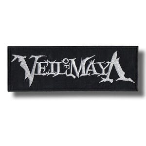 May include: Black rectangular patch with the embroidered text "VEIL OF MAYA" in white. The text has a stylized, gothic font. The patch is likely for clothing or accessories.