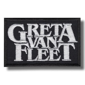 Może przedstawiać: Prostokątna czarna naszywka z haftowanym białym napisem "GRETA VAN FLEET". Tekst jest ułożony w stos, z "GRETA" na górze, "VAN" pośrodku i "FLEET" na dole. Naszywka ma czarną obwódkę.