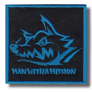May include: Square black patch with a blue border and a blue embroidered wolf-like creature design. The text "MAN WITH A MISSION" is embroidered in white at the bottom of the patch.