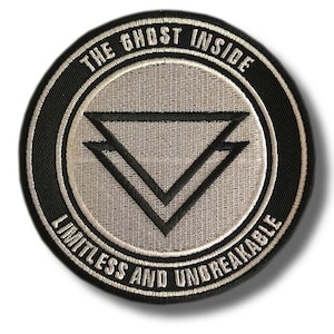 Op de afbeelding: Ronde patch met de tekst "THE GHOST INSIDE" bovenaan en "LIMITLESS AND UNBREAKABLE" onderaan. Het midden heeft een dubbel omgekeerd driehoekontwerp. De patch heeft een zwarte rand en een lichtgrijze binnenkant.