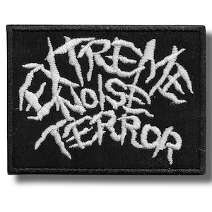 Op de afbeelding: Zwart rechthoekig embleem met witte geborduurde tekst die luidt: "Extreme Noise Terror". De tekst is in een gestileerd, gekarteld lettertype. Het embleem heeft een zwarte rand en is bedoeld voor kleding of accessoires.