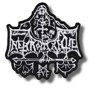 May include: Black and white embroidered patch with the word "NERKROK" in a gothic font. The patch features intricate designs including a cross, a pentagram, and other symbols. The patch has a black border and a white background.