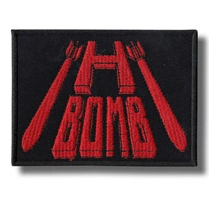 May include: Black rectangular patch with red embroidered text and graphics. The text reads "H BOMB" in a bold, stylized font. Two red missile-like graphics flank the "H". The patch has a black border.