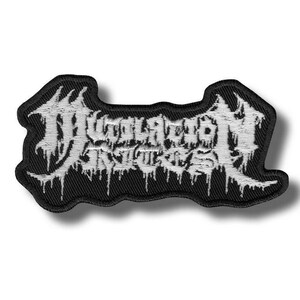Puede incluir: Parche bordado negro con texto blanco. El parche presenta un diseño de fuente gótica estilizada con un efecto de goteo. El parche es rectangular con una parte superior e inferior curvadas.