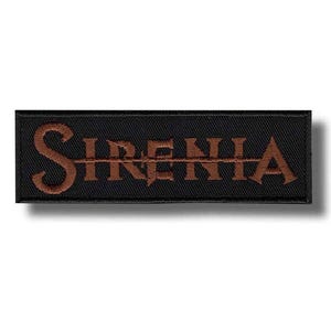 Puede incluir: Un parche rectangular negro con la palabra "SIRENIA" bordada en hilo marrón. El texto está centrado y tiene un estilo de fuente gótica. El parche tiene un borde negro.