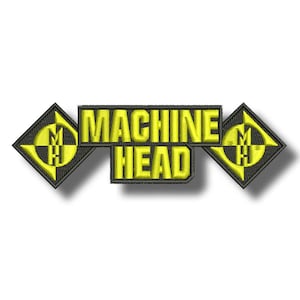 Op de afbeelding: Geborduurde patch met de tekst "MACHINE HEAD" in gele blokletters. De tekst wordt geflankeerd door twee zwart-gele ruitvormige emblemen. De emblemen hebben een gestileerd "M H"-ontwerp.