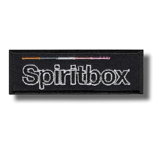 May include: Black rectangular patch with the word "Spiritbox" embroidered in white. A thin horizontal line of orange, blue, and pink thread is above the text. The patch has a black border and a shadow.