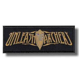 May include: A rectangular black patch with gold embroidered text that reads "UNLEASH ARCHERS". A gold shield design is centered, with the text "THE ARCHERS" in the center. The patch has a slight shadow.