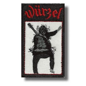 Op de afbeelding: Geborduurde patch met het woord "Würzel" in rood schrift. Het heeft een zwart-wit illustratie van een figuur met een gitaar in een dynamische pose. Zwarte rand met rode stiksels, voor kleding of accessoires.