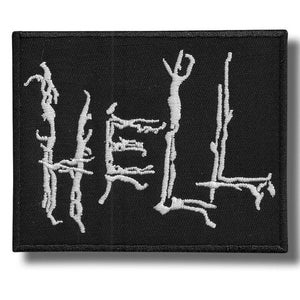 Può includere: Toppa rettangolare nera con la scritta "HELL" ricamata in bianco, con caratteri gotici stilizzati. La toppa ha un bordo nero ed è progettata per essere cucita su abiti o accessori.