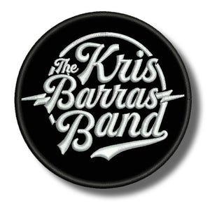 Pode incluir: Um patch redondo preto com texto bordado branco. O texto diz "The Kris Barras Band" em uma fonte cursiva estilizada. Acentos de raios em ambos os lados do nome da banda. O patch tem uma borda preta.