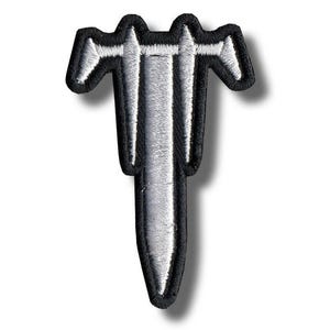 May include: Embroidered patch featuring a stylized silver sword design with a black border. The sword has a detailed, textured appearance, with white accents. The patch is likely for clothing or accessories.