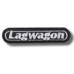 May include: A black rectangular patch with the word "Lagwagon" embroidered in white, outlined in a white border. The patch has a slight shadow, suggesting it is raised from the surface.