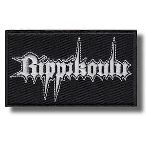 Puede incluir: Parche rectangular negro con la palabra "Rippikoulu" bordada en blanco. El texto está en una fuente gótica con bordes afilados y dentados. Este parche está diseñado para ropa o accesorios.