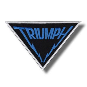 Könnte beinhalten: Ein schwarzer, dreieckiger Aufnäher mit dem Wort "TRIUMPH" in Blau. Der Aufnäher hat einen weißen Rand und blaue Blitz-Akzente. Geeignet für Motorrad- oder Automobil-Enthusiasten.