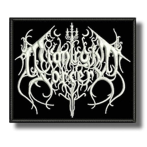 May include: A black rectangular patch with white embroidered text and decorative elements. The text appears to be a band name or logo. The patch has a black border and is likely designed to be sewn or ironed onto clothing or accessories.