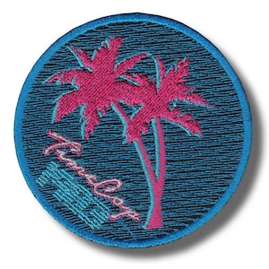 Könnte beinhalten: Runder, gestickter Aufnäher mit einem rosa Palmen-Design auf blauem Hintergrund. Der Aufnäher hat einen blauen Rand und den Schriftzug "Timeless" in einer stilisierten Schriftart. Ideal für Jacken, Taschen oder andere Textilartikel.
