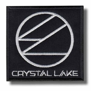 May include: Black square patch with white embroidered design and text. The design features a circle with diagonal lines and the text "CRYSTAL LAKE" below. The patch has a black border and is likely an iron-on or sew-on patch.