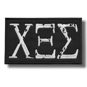 Könnte beinhalten: Schwarzer rechteckiger Aufnäher mit den gestickten griechischen Buchstaben X, E und Σ in Weiß. Die Buchstaben haben ein verwittertes, strukturiertes Aussehen. Geeignet für Kleidung oder Accessoires.