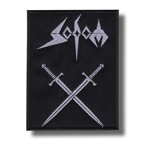 May include: Black embroidered patch featuring the word "Sodom" in a stylized font above two crossed swords. The patch has a rectangular shape with a black background and white stitching.