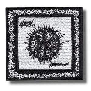 Puede incluir: Parche bordado cuadrado en blanco y negro. El parche presenta un diseño central negro con elementos puntiagudos y texto, rodeado por un borde decorativo. El fondo es blanco.