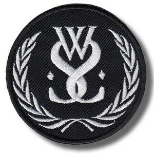 Könnte beinhalten: Runder, schwarzer, gestickter Aufnäher mit einem weißen, verschlungenen Design der Buchstaben "W" und "S" und einem Lorbeerkranz-Rand. Der Aufnäher ist kreisförmig und hat eine strukturierte Oberfläche.
