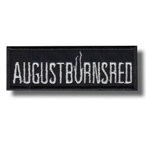 Peut inclure: Un écusson rectangulaire noir avec le texte brodé "AUGUST BURNS RED" en blanc. Le patch présente un design simple et épuré, adapté à une application sur des vêtements ou des accessoires.