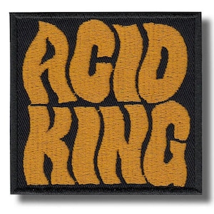 May include: Square black patch with the words "ACID KING" embroidered in a wavy, mustard yellow font. The patch has a black border and a slight shadow effect, giving it a raised appearance.