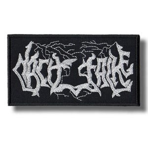 May include: Black rectangular patch with white embroidered text that reads "OBSECRATE" in a gothic font. The patch has a black border and a white background for the text. The design is a stylized, heavy metal band logo.
