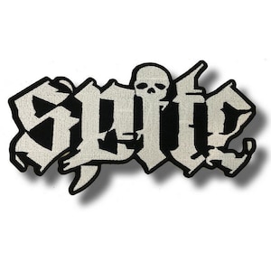 May include: A black and white embroidered patch featuring the word "Spite" in a gothic font, with a skull replacing the "i". The patch has a black border and is set against a white background.