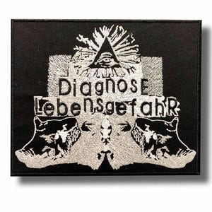 Peut inclure: Écusson brodé noir avec les mots "Diagnose Lebensgefahr" en fil argenté. L'écusson présente un œil dans un triangle et deux figures d'animaux stylisées. L'écusson est rectangulaire.