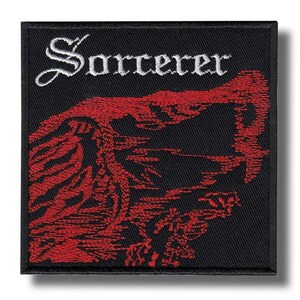 Op de afbeelding: Vierkantige zwarte patch met het woord "Sorcerer" in witte letters bovenaan. Een gedetailleerde rode illustratie van een wezen of landschap vult het onderste deel van de patch. De patch heeft een zwarte rand.