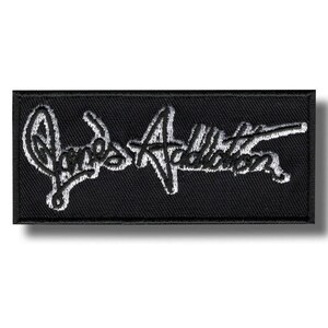 Könnte beinhalten: Schwarzer rechteckiger Aufnäher mit dem gestickten Text "Jane's Addiction" in weißer Schrift. Der Aufnäher hat einen schwarzen Rand und ein strukturiertes Aussehen.